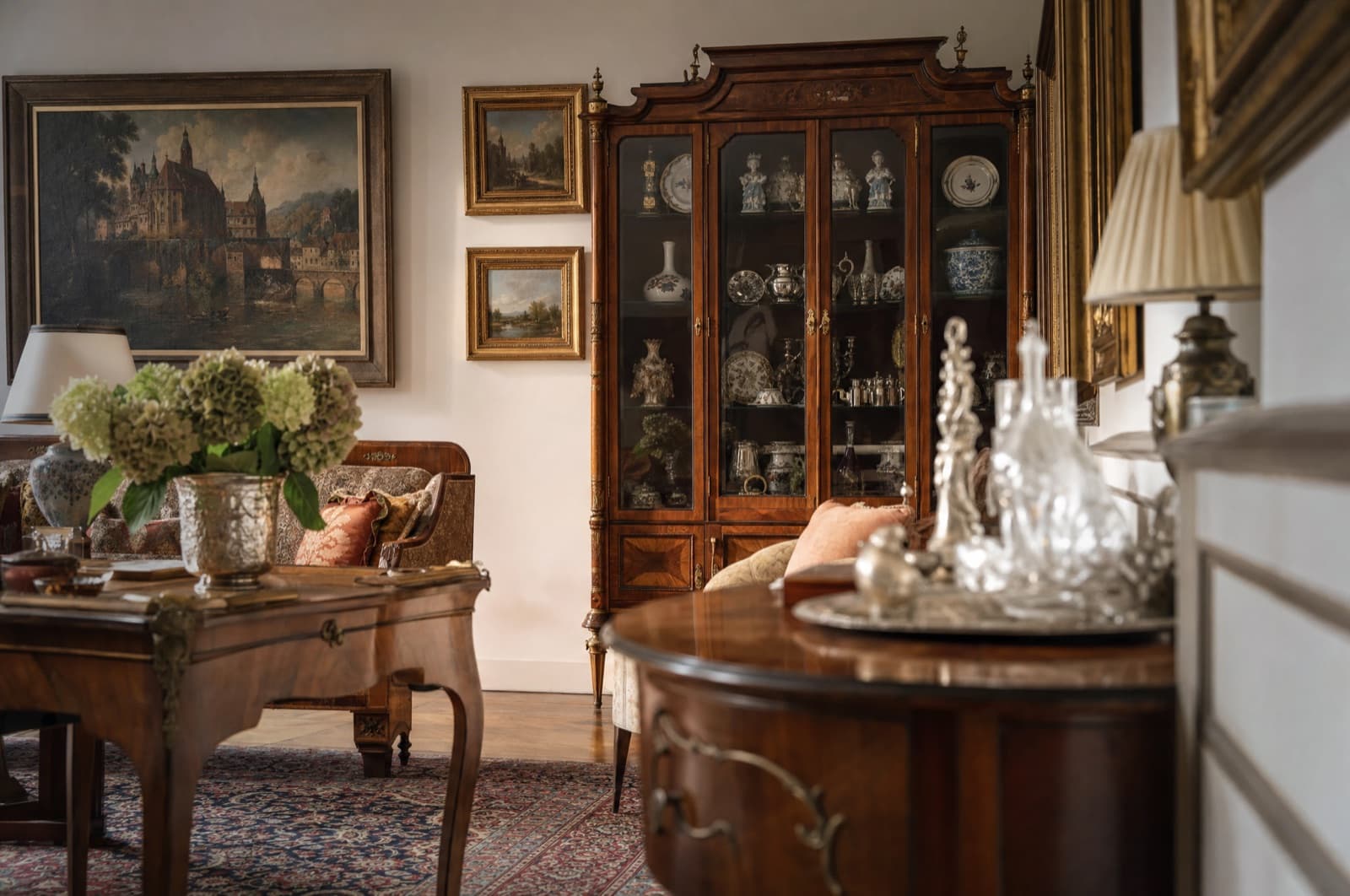 Elegantes Wohnzimmer mit Antiquitäten, Vitrine und Gemälden